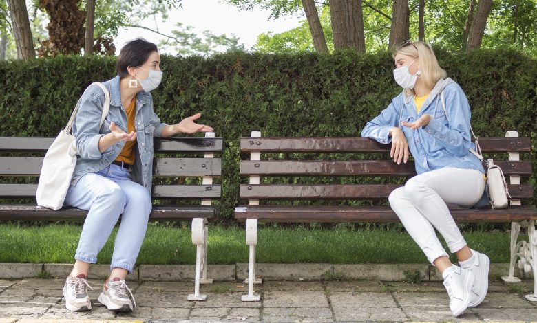 2 mujeres con distancia social hablando en un parque